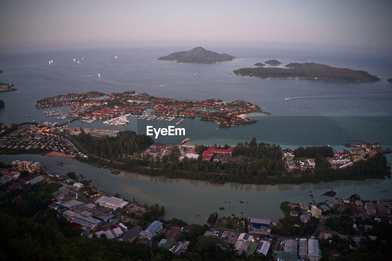 Drone field of view of sunset over ocean and town of mahe from on top of lookout in the seychelles.