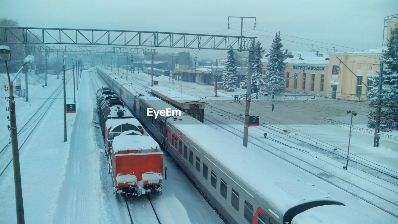 Trains on snow covered field against sky