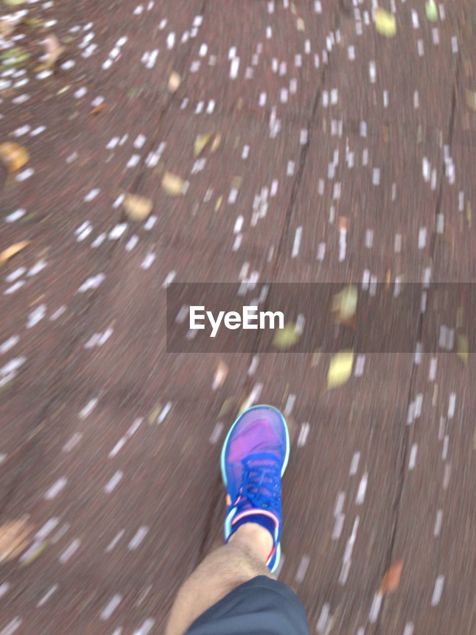 Low section of man running on fallen flowers on footpath