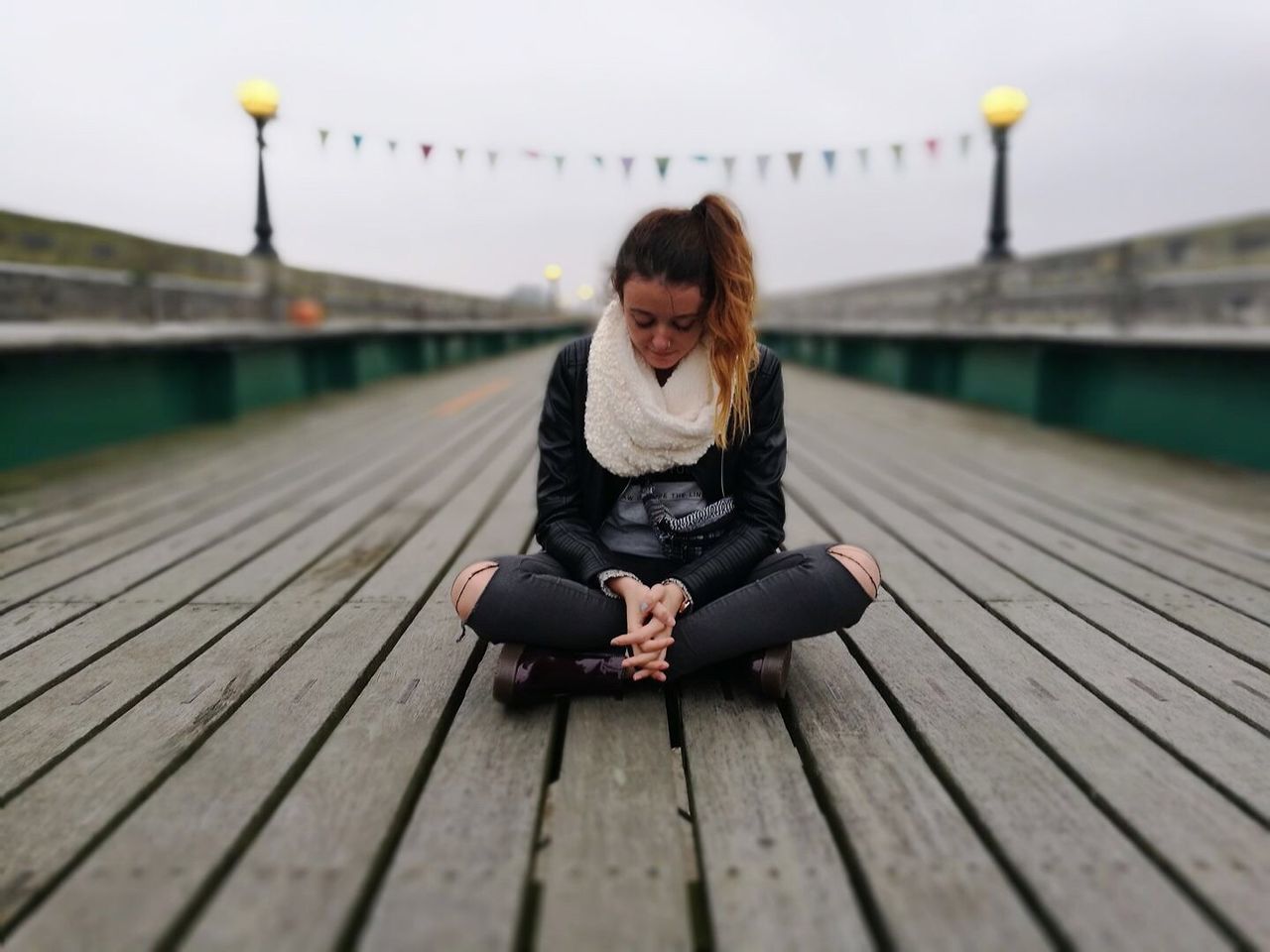 FULL LENGTH OF MAN SITTING ON PIER AT JETTY