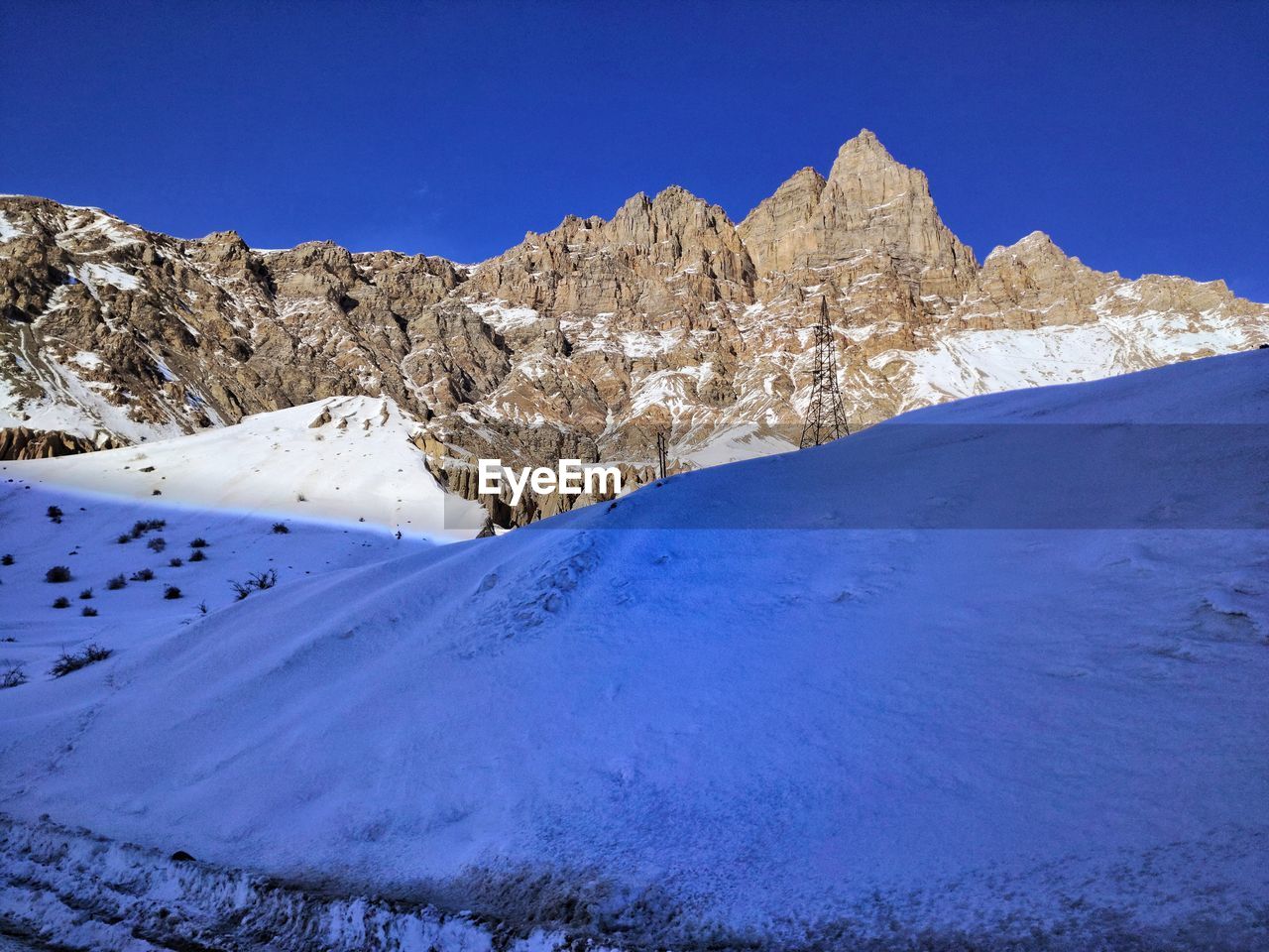 Scenic view of snowcapped mountains against clear blue sky