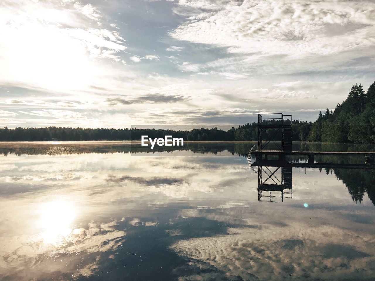 Pier reflecting on calm lake against sky