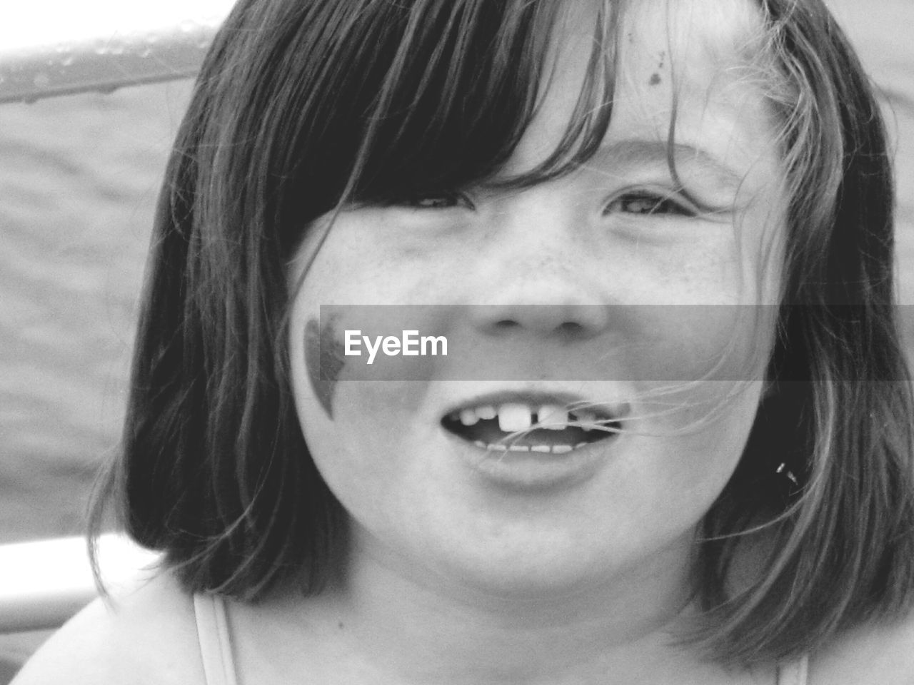 Close-up portrait of girl smiling by railing