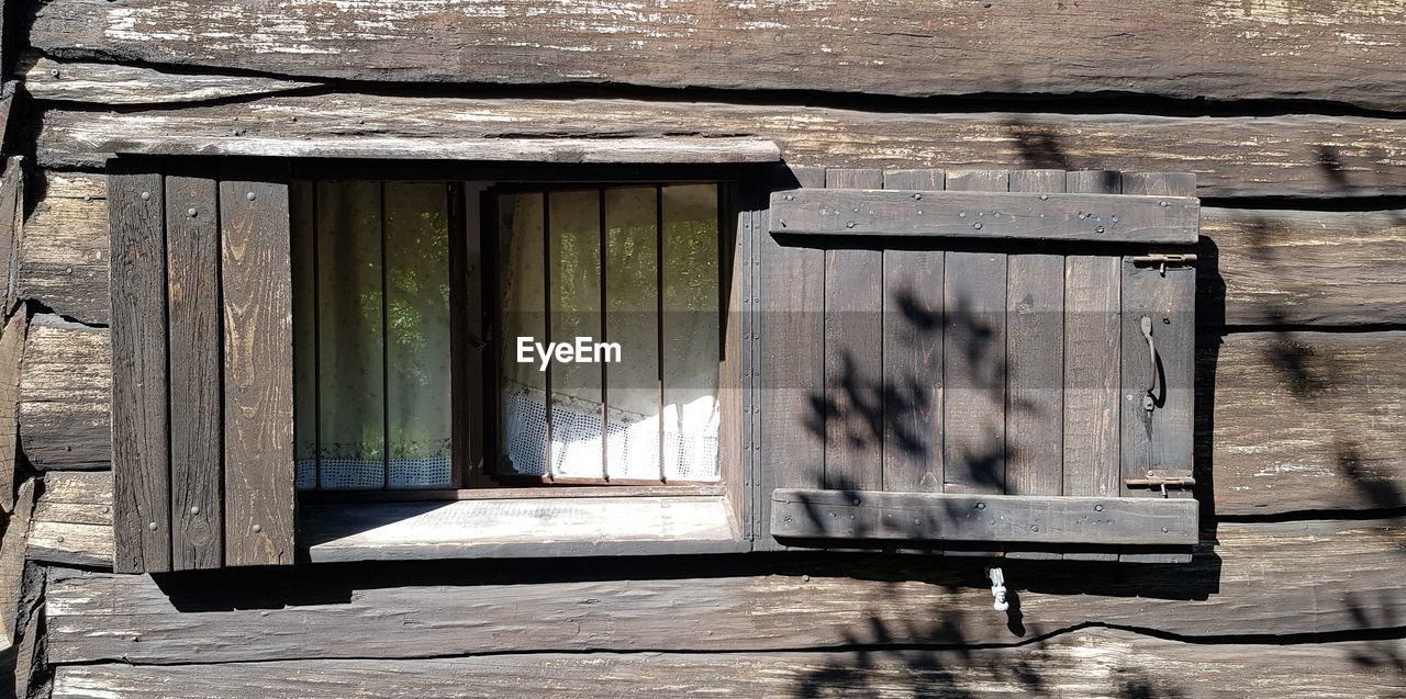 Close-up of open window on wooden door of building
