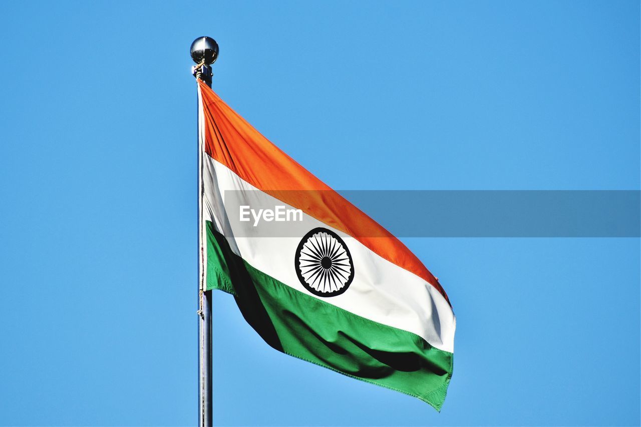 Low angle view of flag against clear blue sky