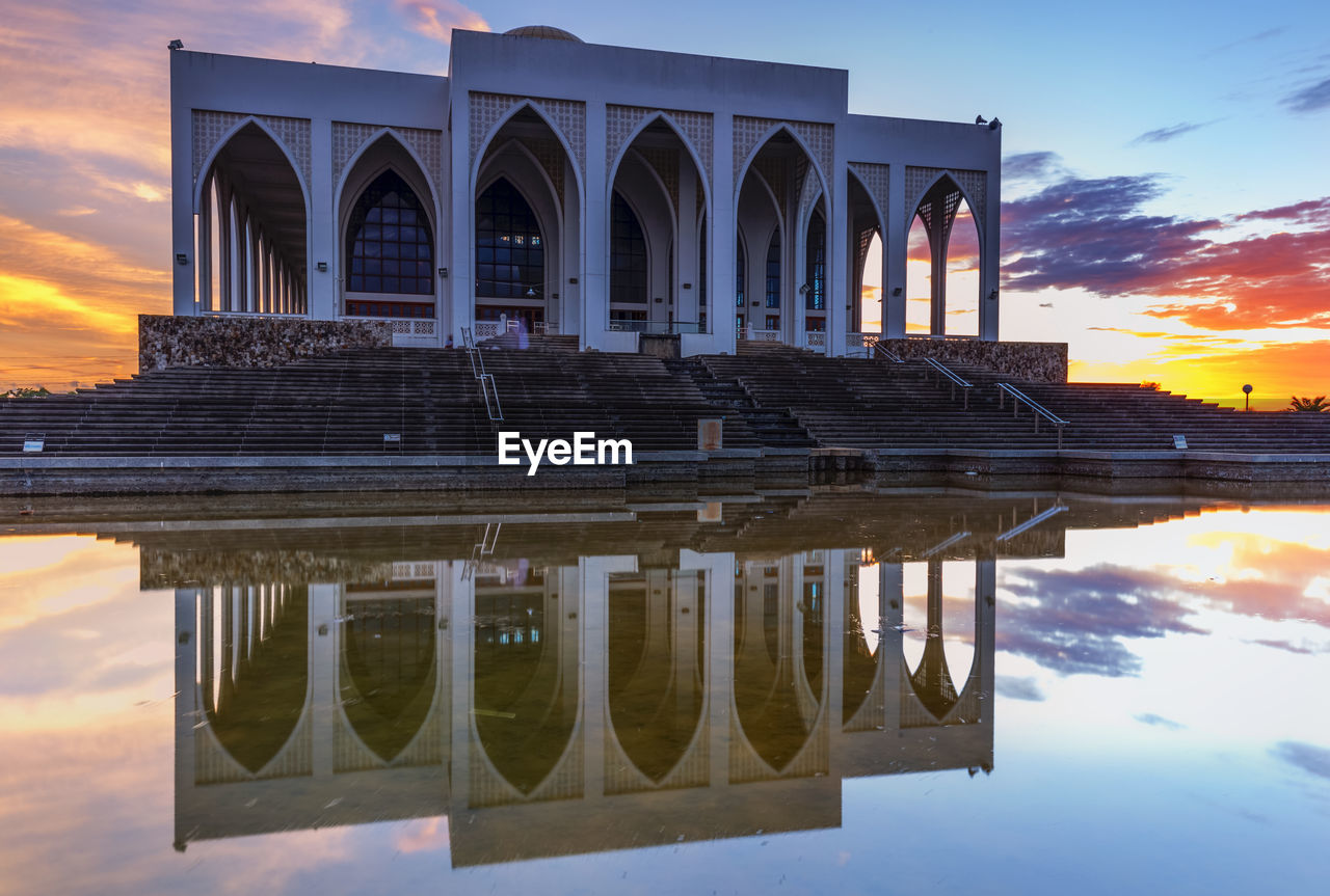 Historical building reflecting in pool during sunset