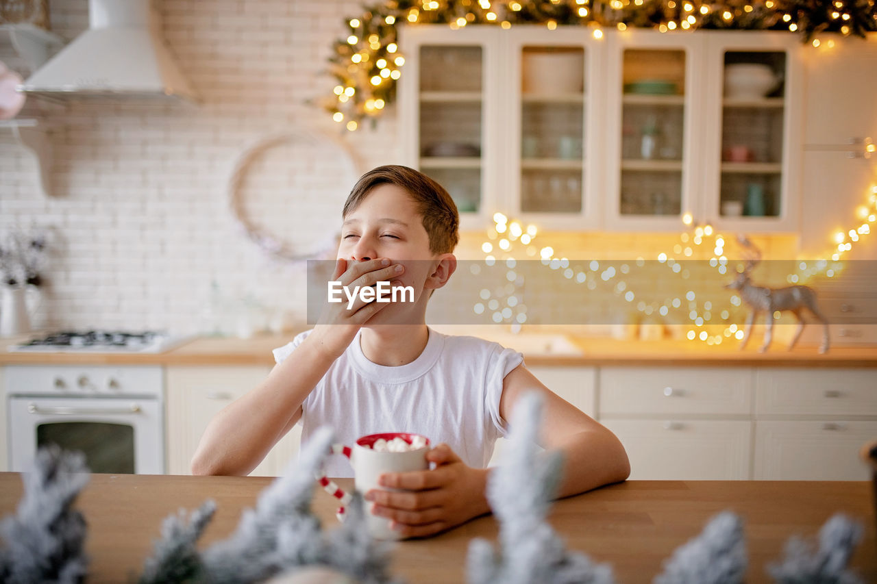 Boy drinking on table at home