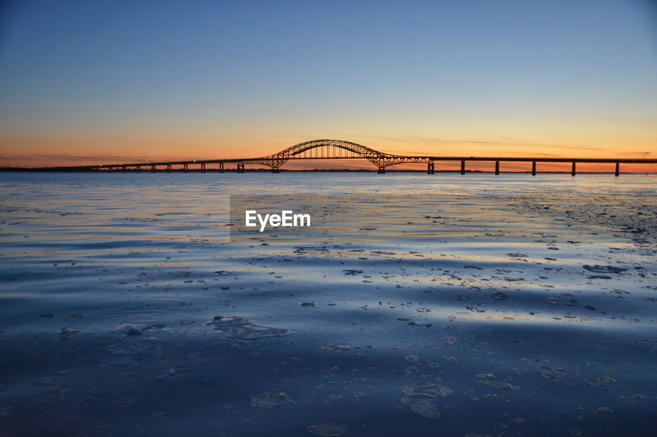 Bridge over river against sky during sunset