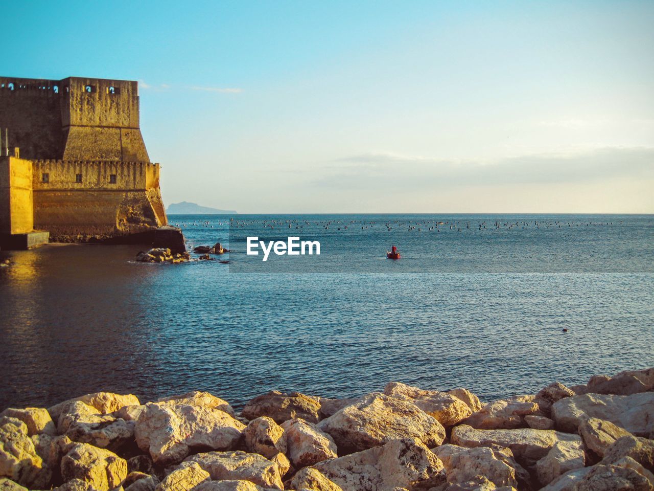 Castel dell ovo by sea against sky