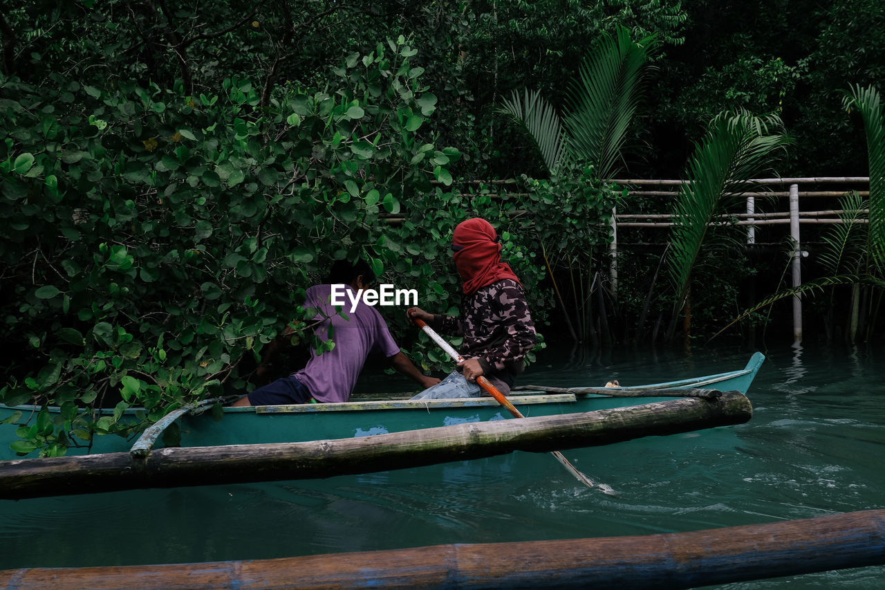 People in boat against trees