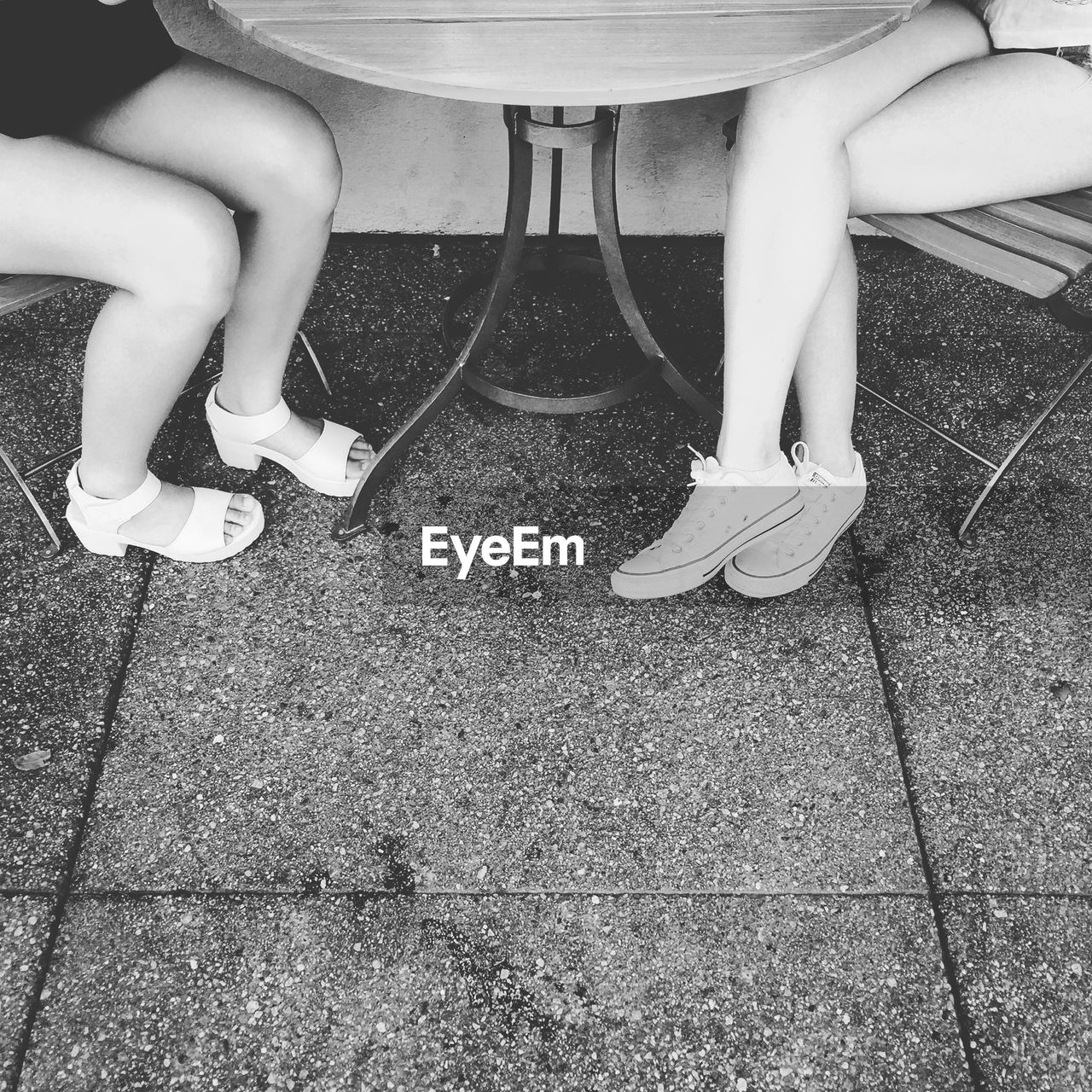 Low section of women sitting on chair by table at sidewalk cafe
