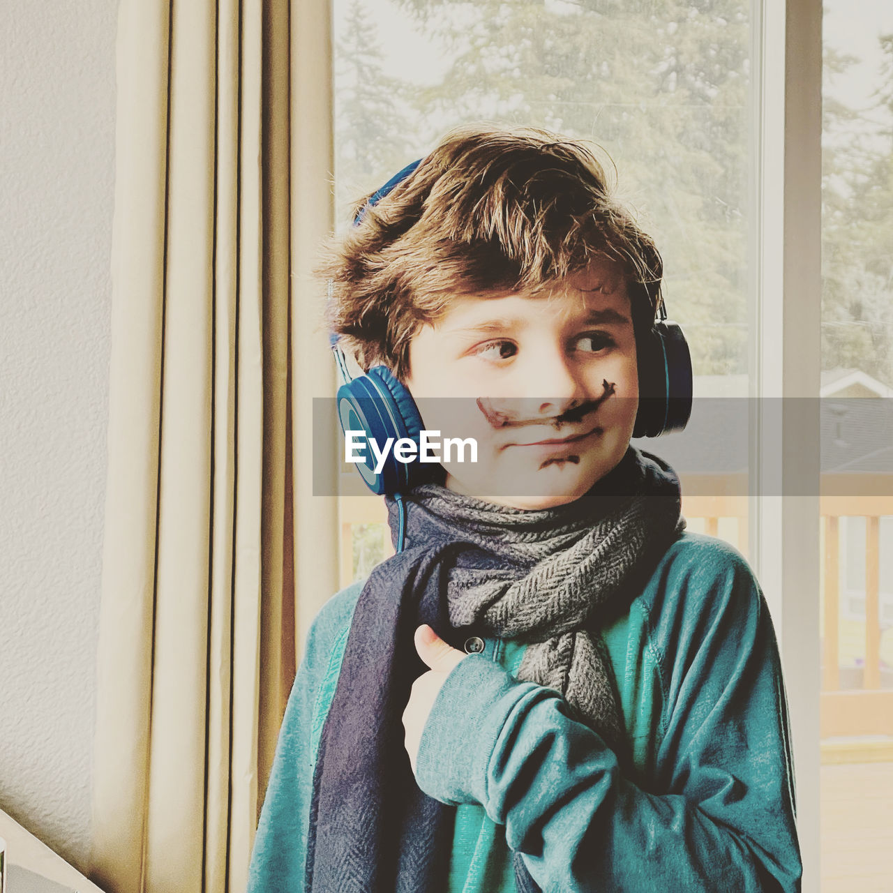 Portrait of boy looking through window at home