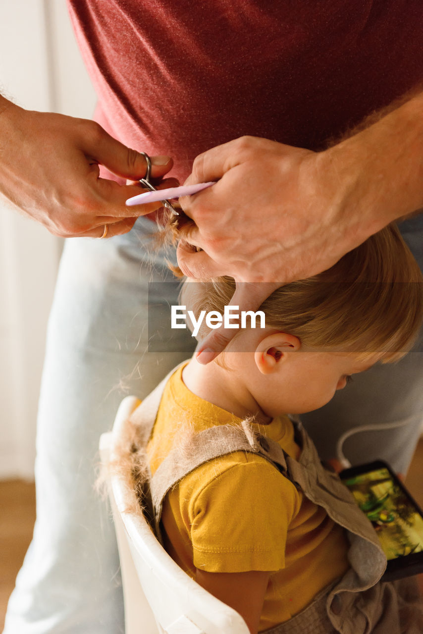 Dad cutting hair to little son