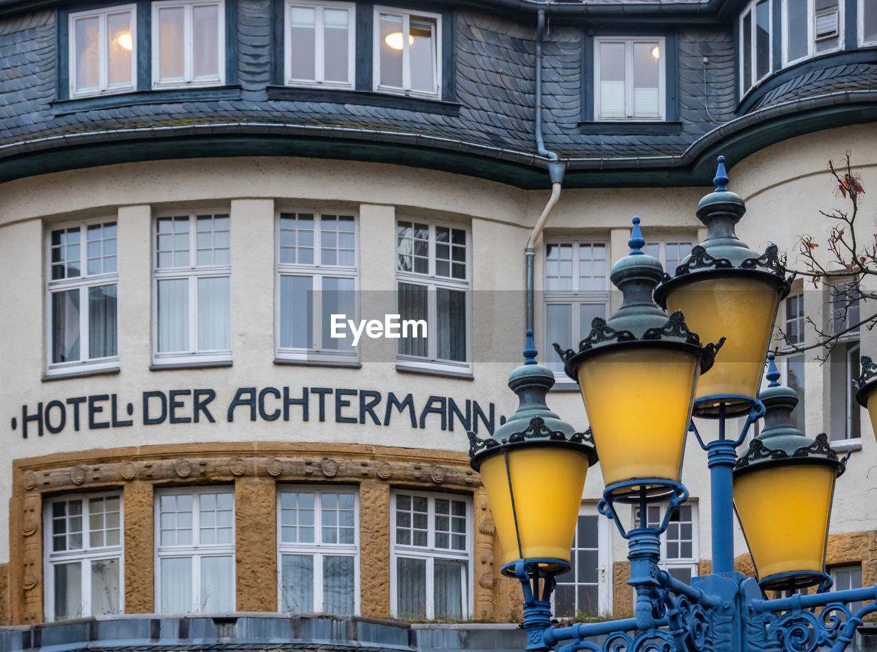 LOW ANGLE VIEW OF ILLUMINATED STREET LIGHT BY BUILDING