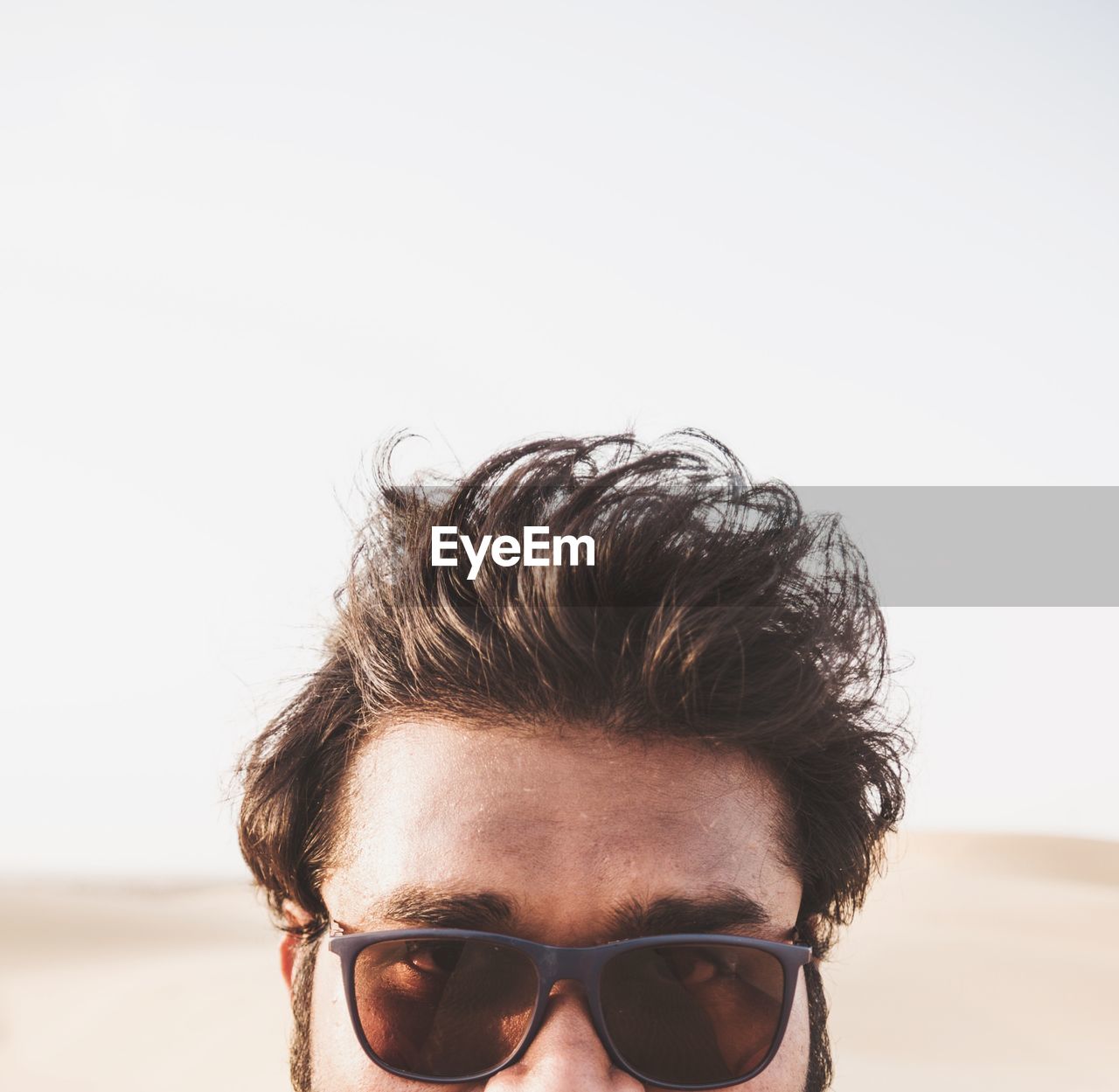 CLOSE-UP PORTRAIT OF YOUNG MAN WEARING SUNGLASSES AGAINST CLEAR SKY