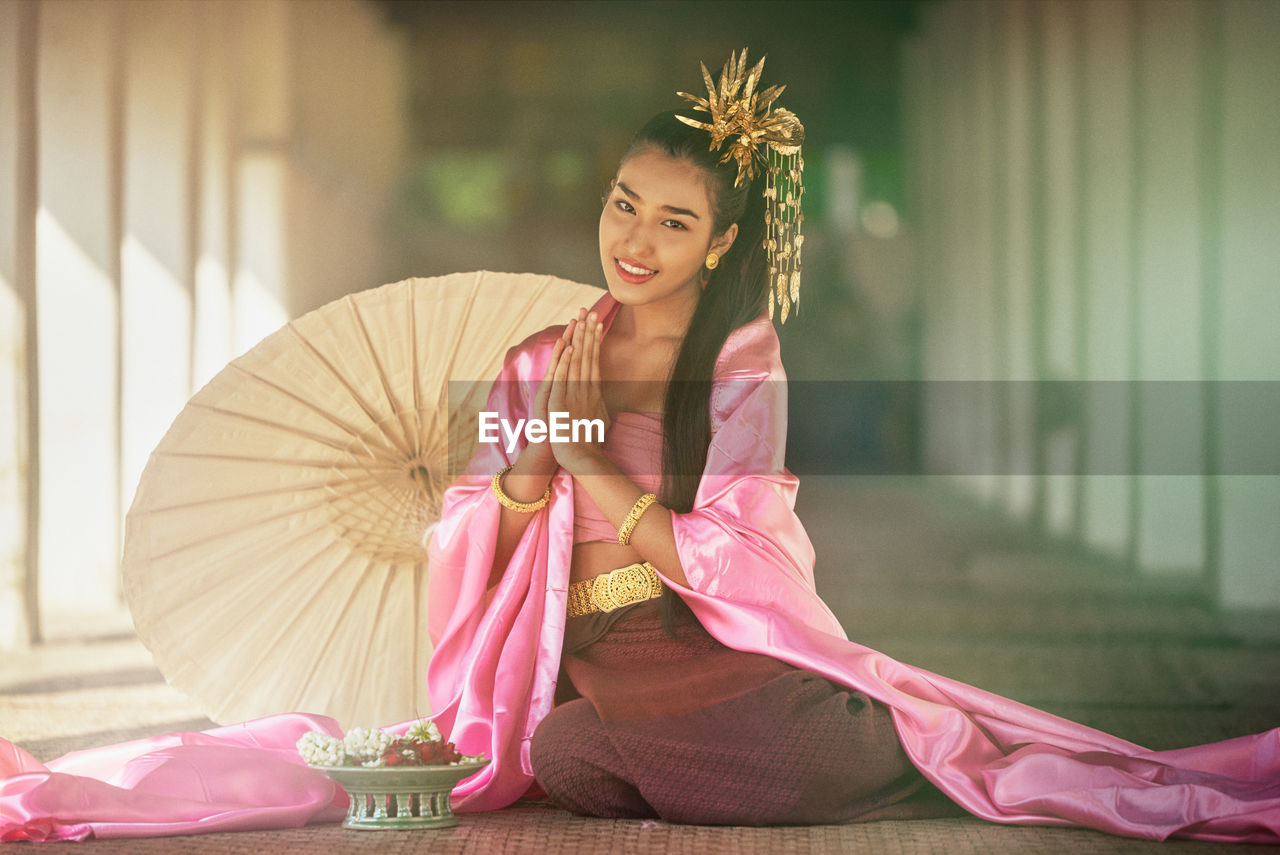 Portrait of smiling girl wearing costume sitting at temple