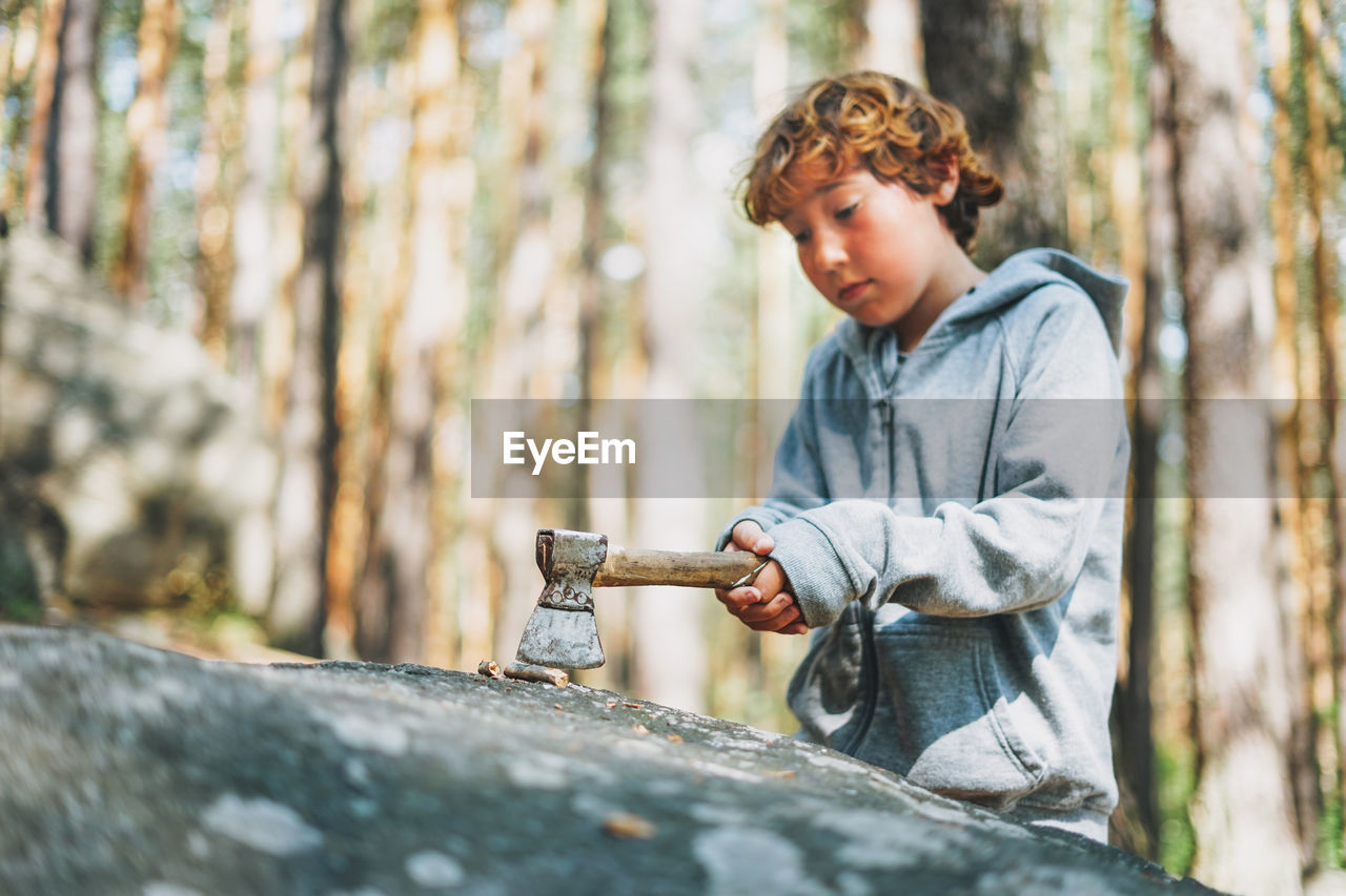 Boy looking at tree trunk in forest