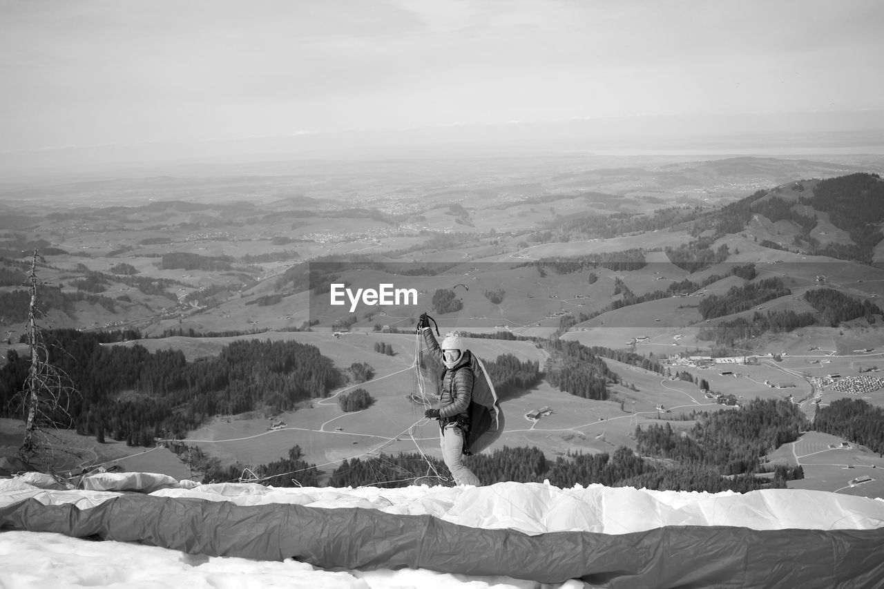 Man with parachute on mountain against sky