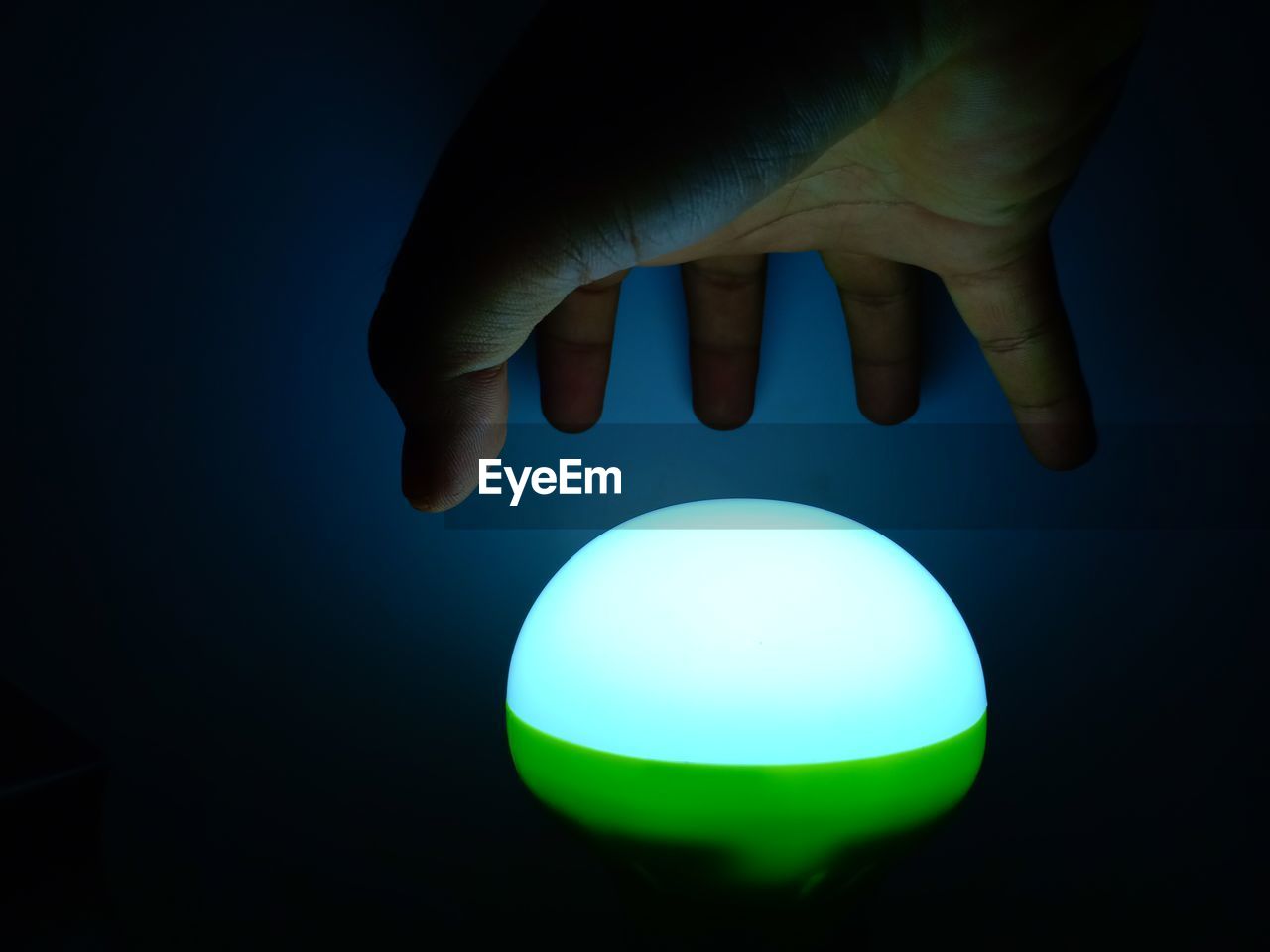 CLOSE-UP OF HAND HOLDING ILLUMINATED LIGHTING EQUIPMENT