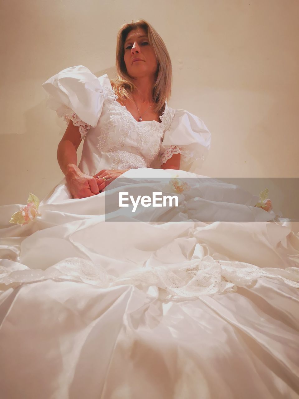 Portrait of bride sitting against wall