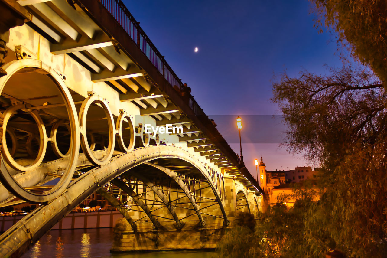 Low angle view of illuminated bridge against sky at night