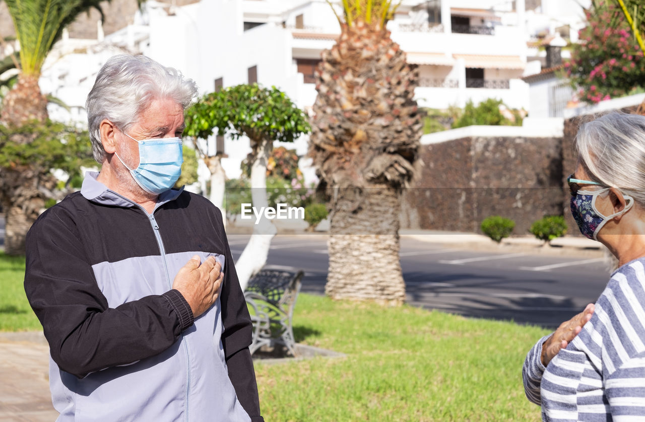 Senior couple wearing mask standing outdoors