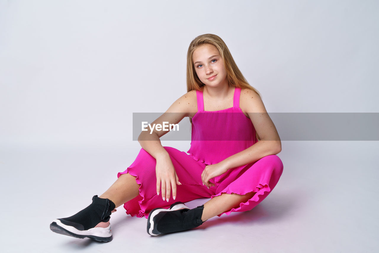 Young girl posing in a pink suit on a white background sitting person