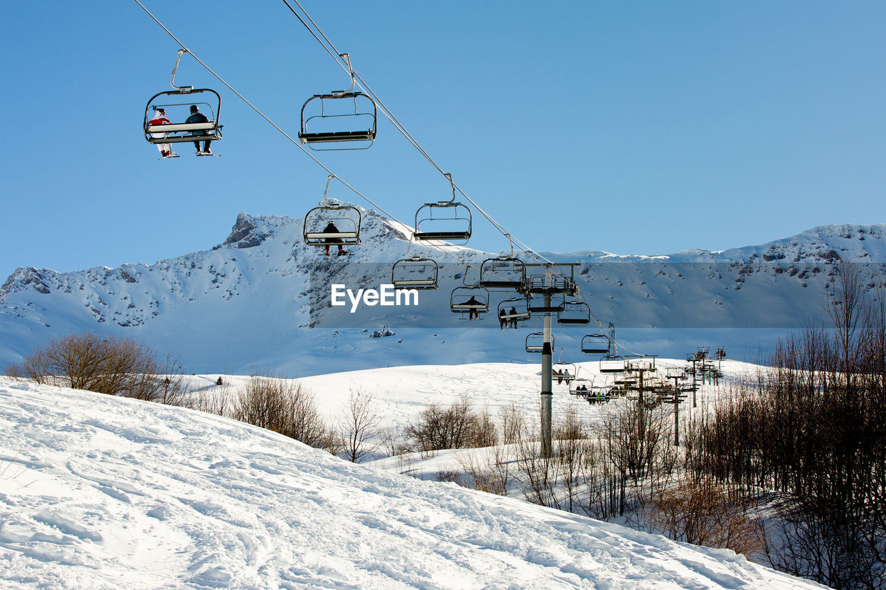 OVERHEAD CABLE CAR AGAINST SNOW COVERED MOUNTAINS AGAINST SKY