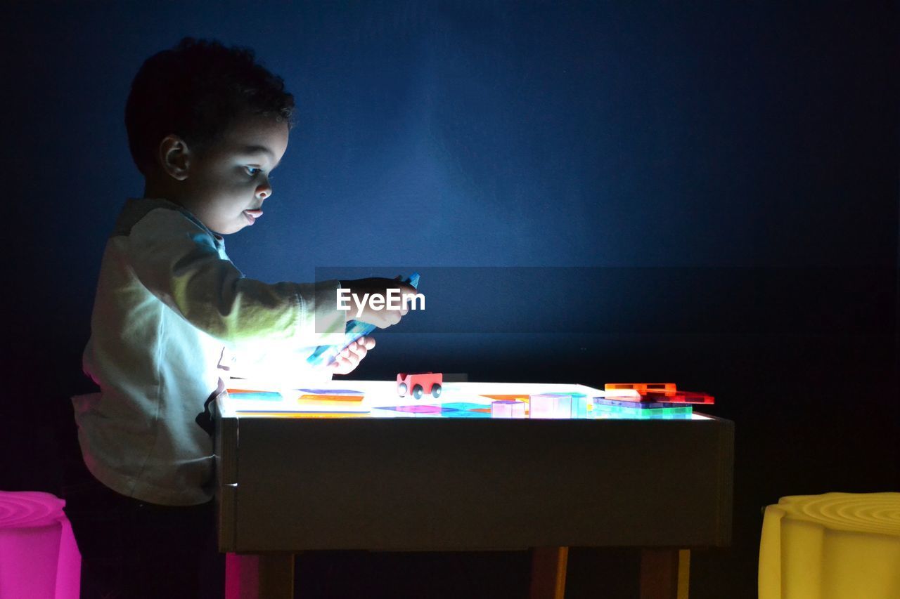 Side view of boy playing with toys in room