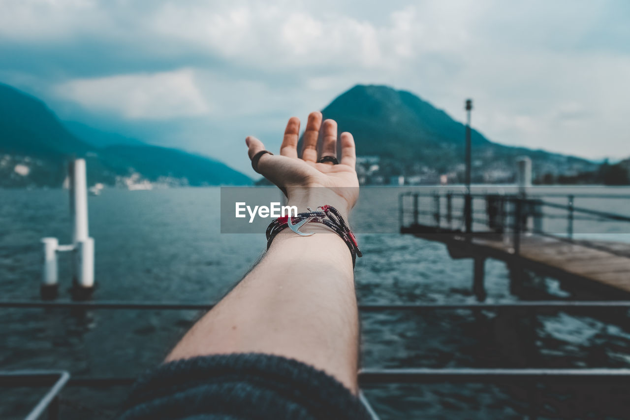 Close-up of woman hand against sea 