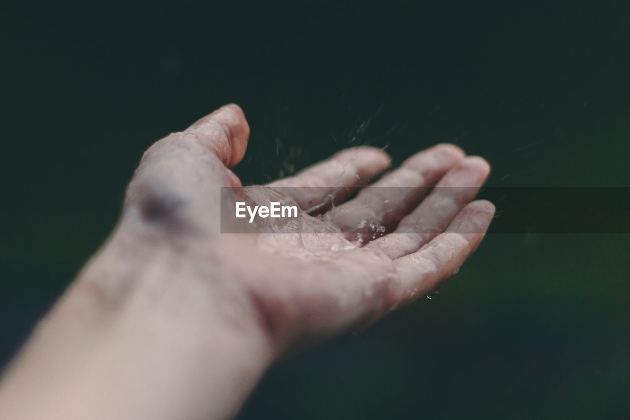 Close-up of water drops on hand against blurred background