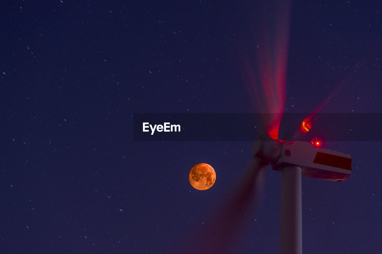 Wind wheels in front of blood moon at night