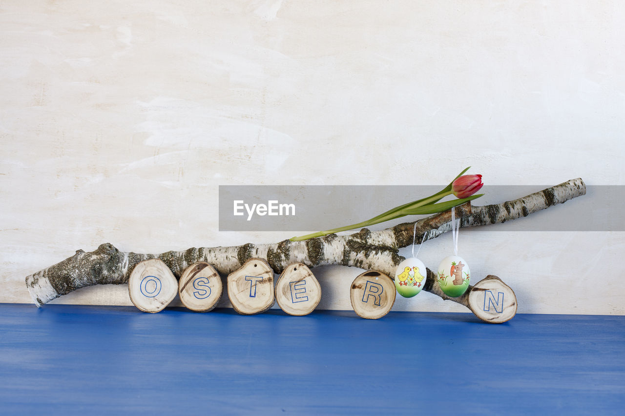 Wooden decoration with text on blue table against wall during easter