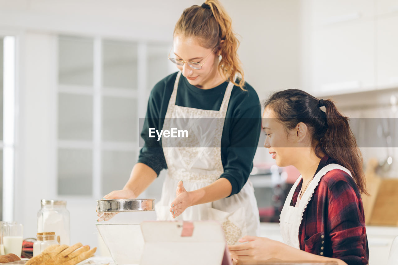 Young woman holding food while standing on table