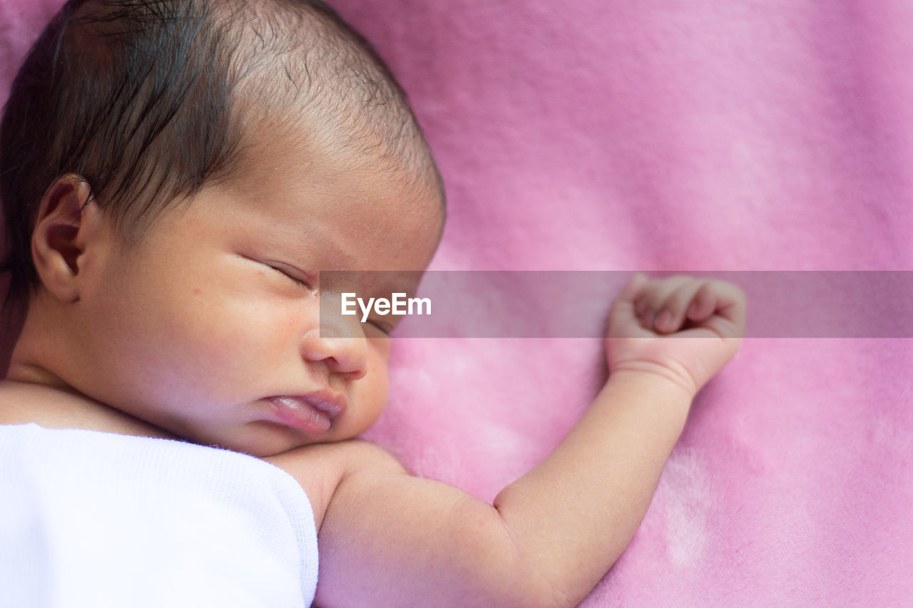 Close-up of baby girl sleeping on bed