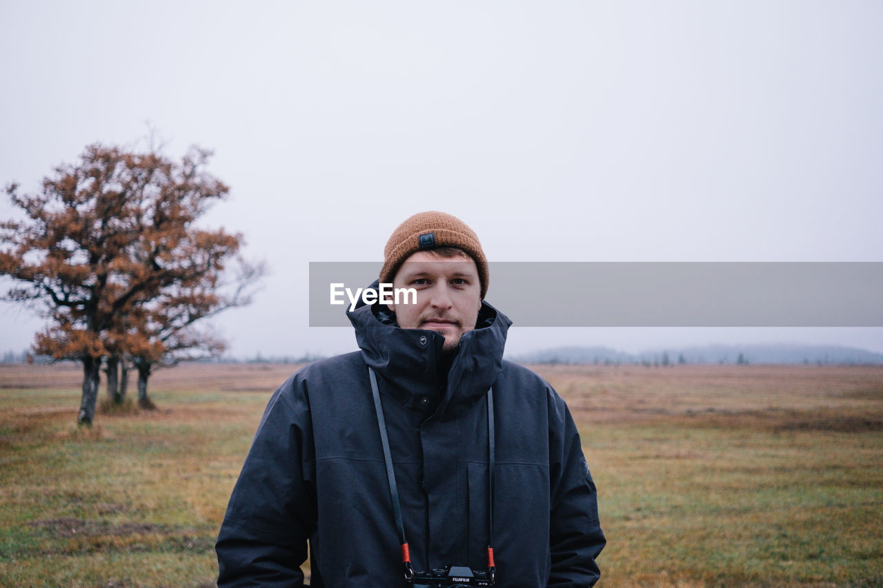 Portrait of man standing on field against sky during winter