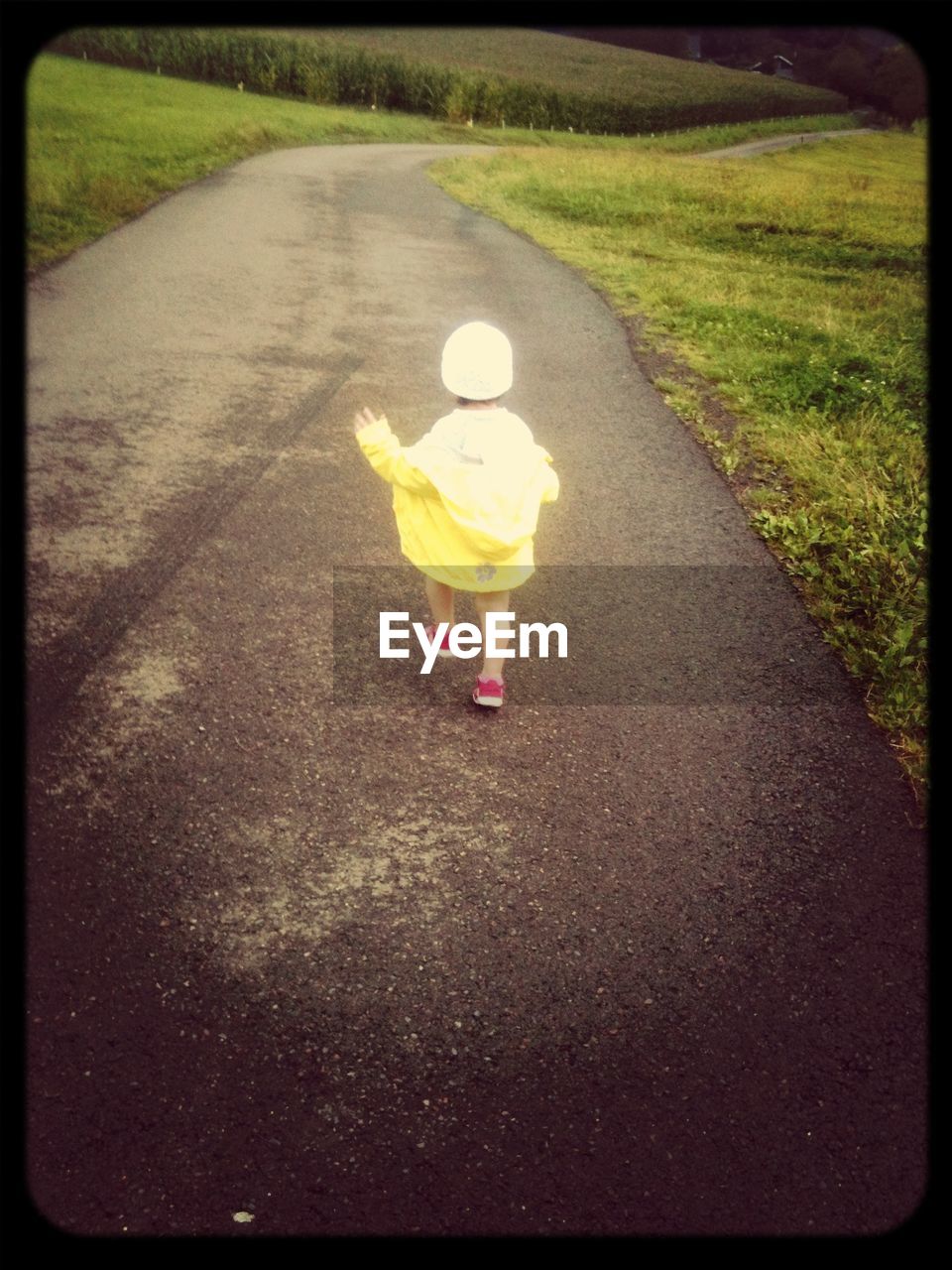 Rear view of little girl walking along road