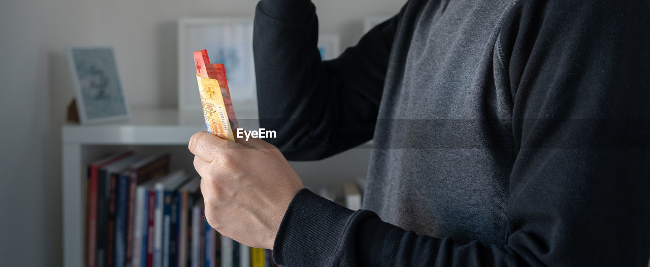 Midsection of man holding money at home