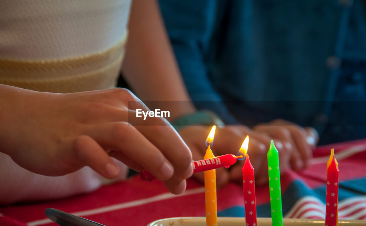 Close-up of girl lighting birthday candles