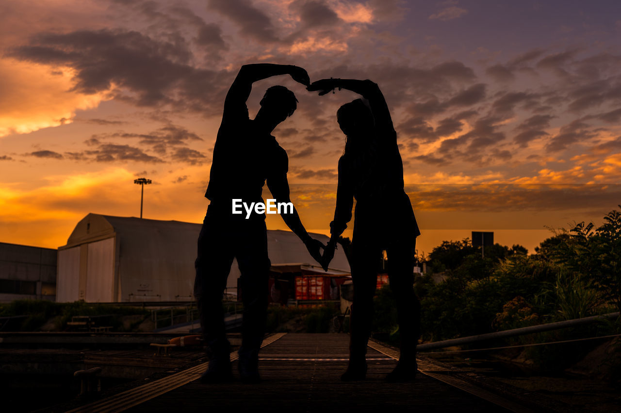 sunset, sky, silhouette, cloud, evening, two people, architecture, adult, nature, love, women, sunlight, positive emotion, emotion, dusk, men, togetherness, lifestyles, person, built structure, orange color, city, outdoors, standing, full length