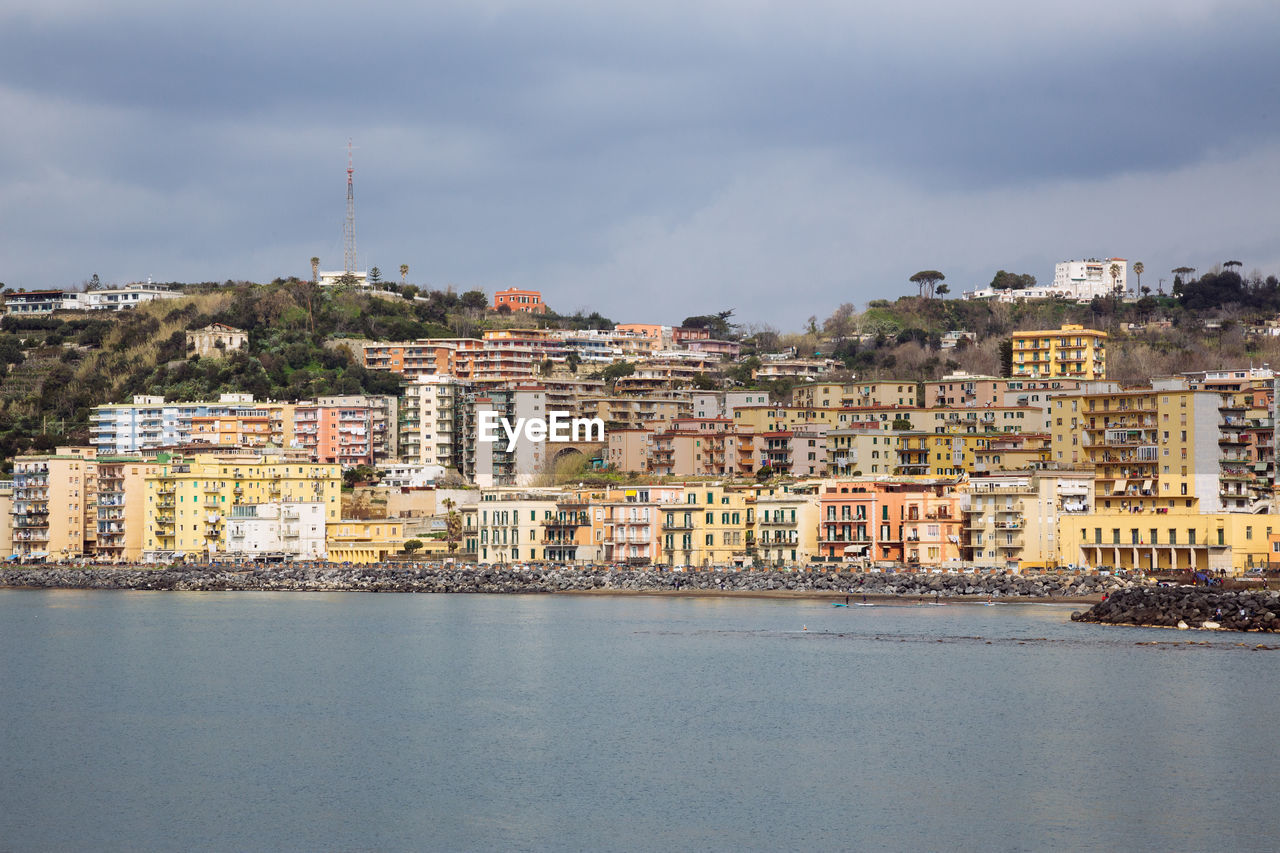 BUILDINGS BY RIVER AGAINST SKY