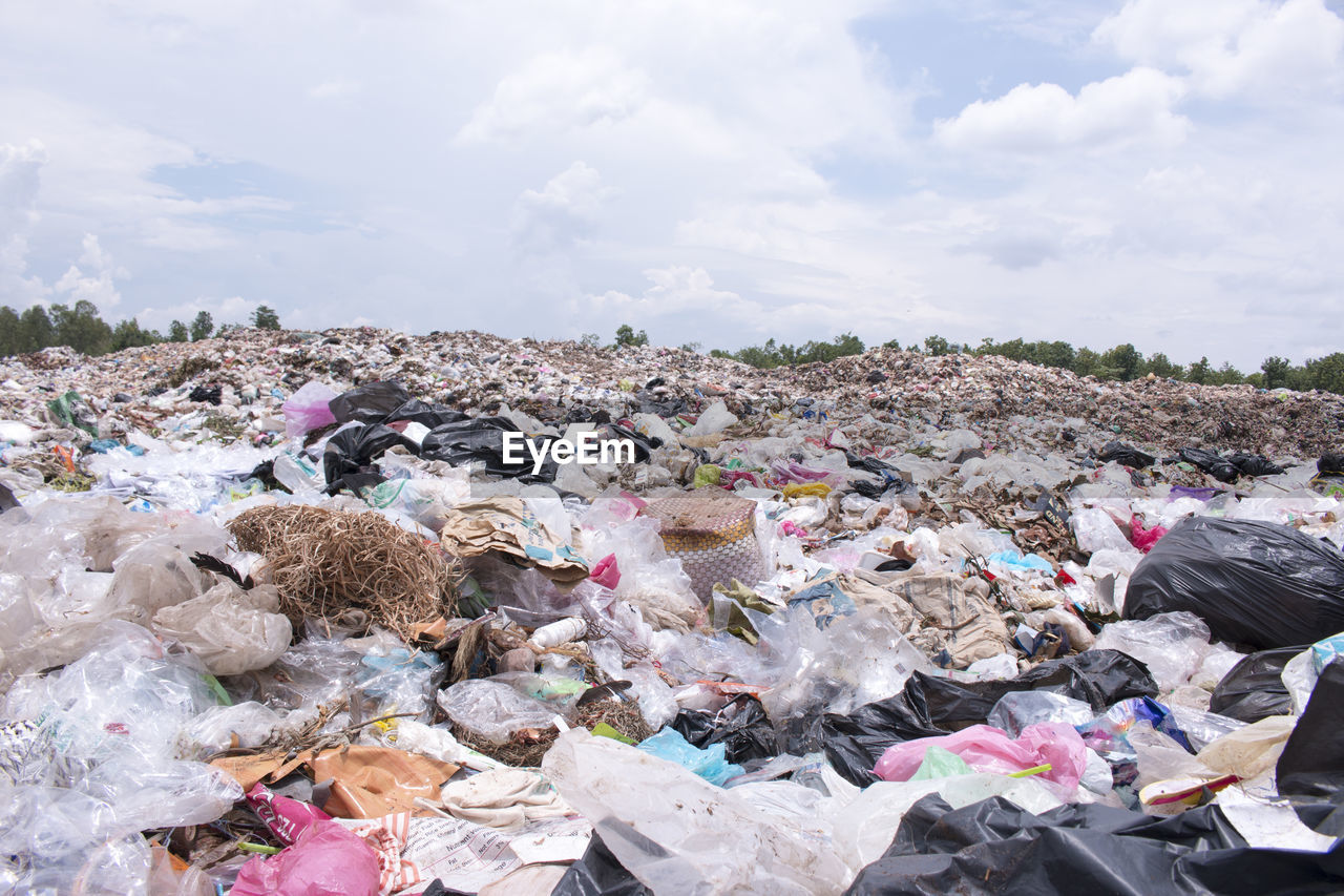 Heap of garbage against cloudy sky at recycling center