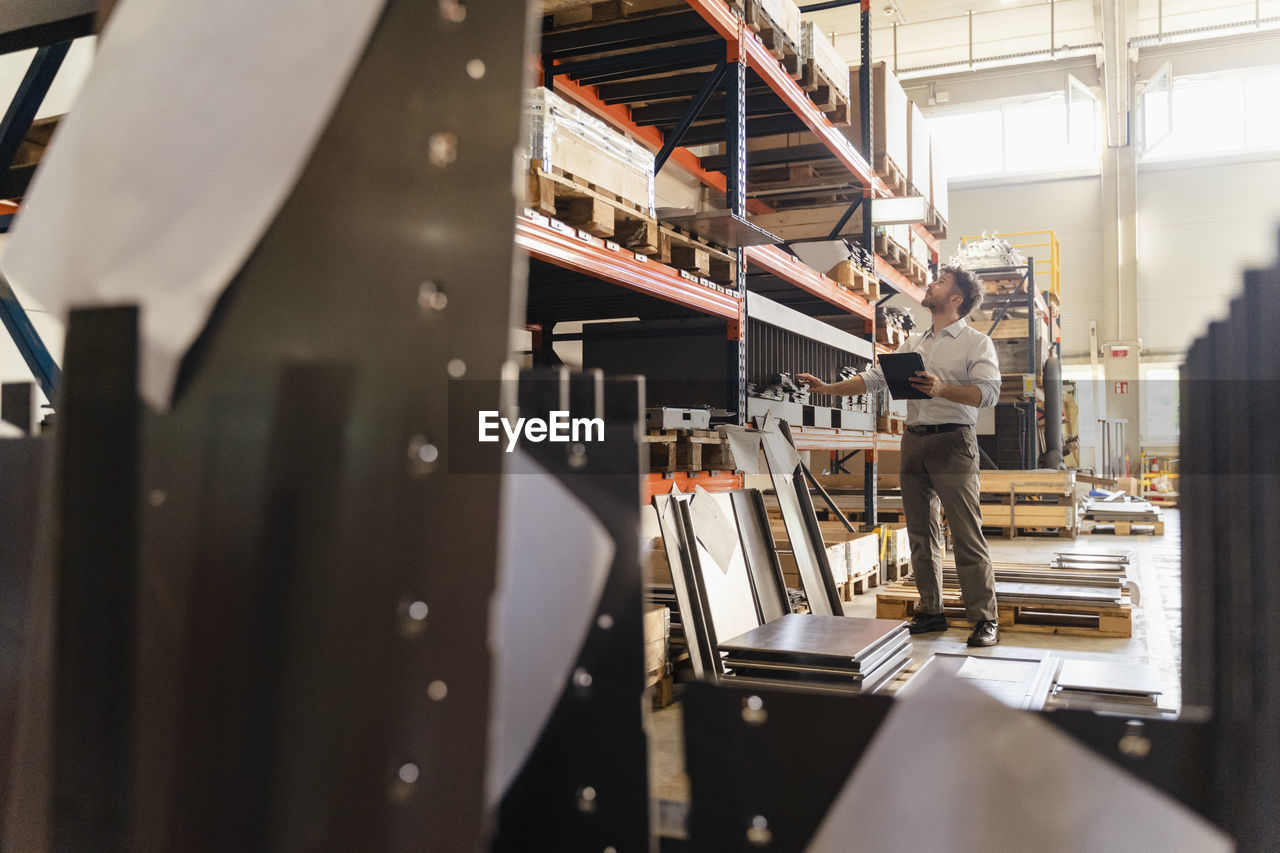 Businessman checking warehouse material while standing at factory