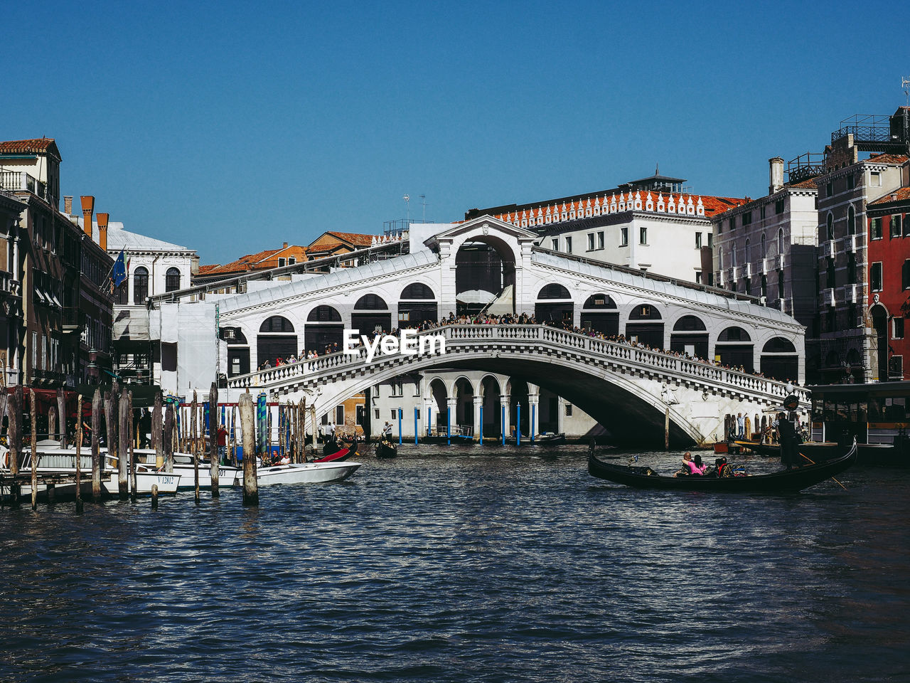 Arch bridge over canal in city against clear sky