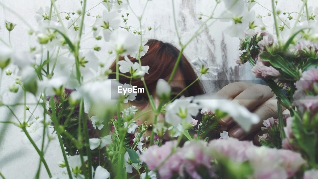 Portrait of woman seen through flowers outdoors