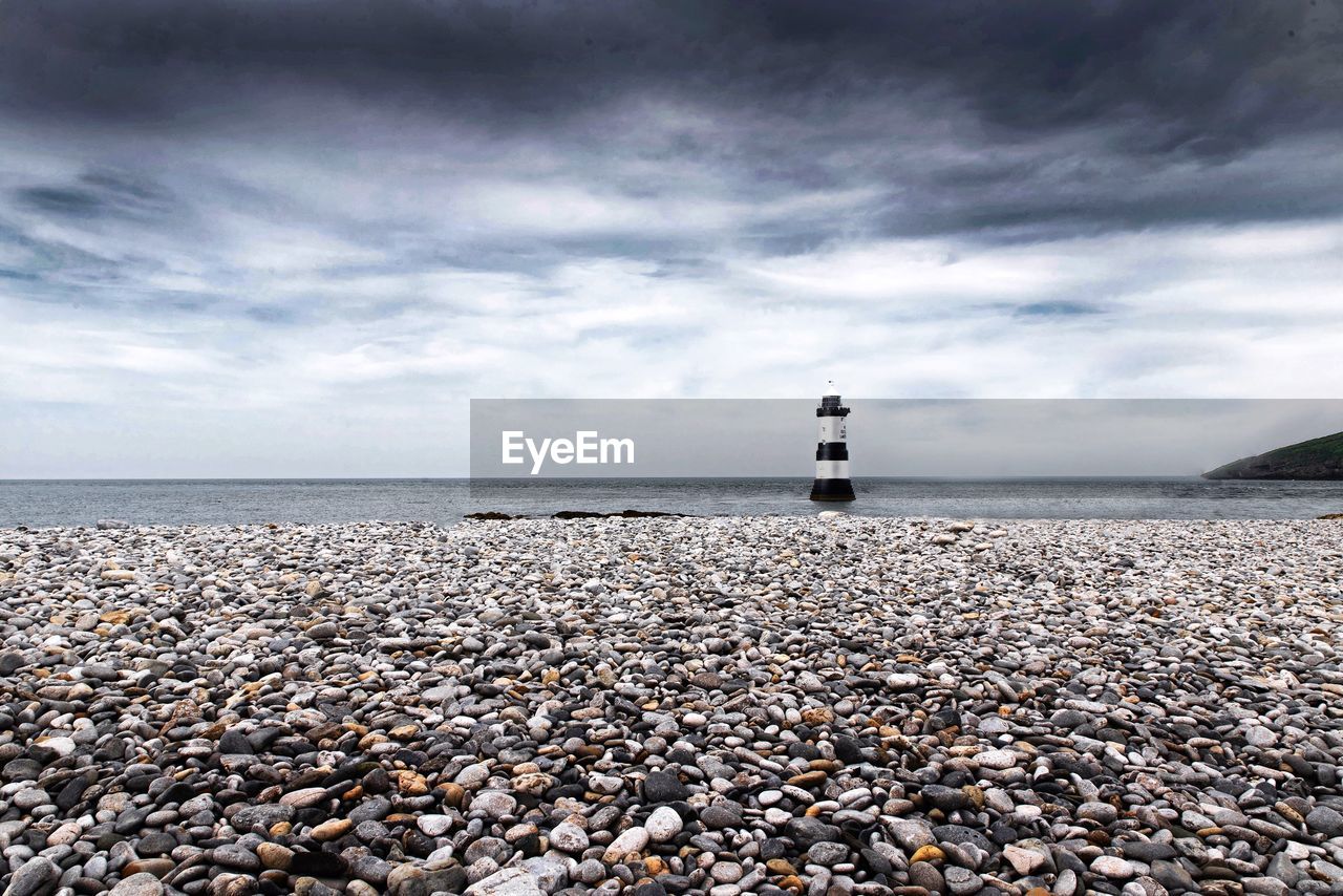 Lighthouse on beach against sky