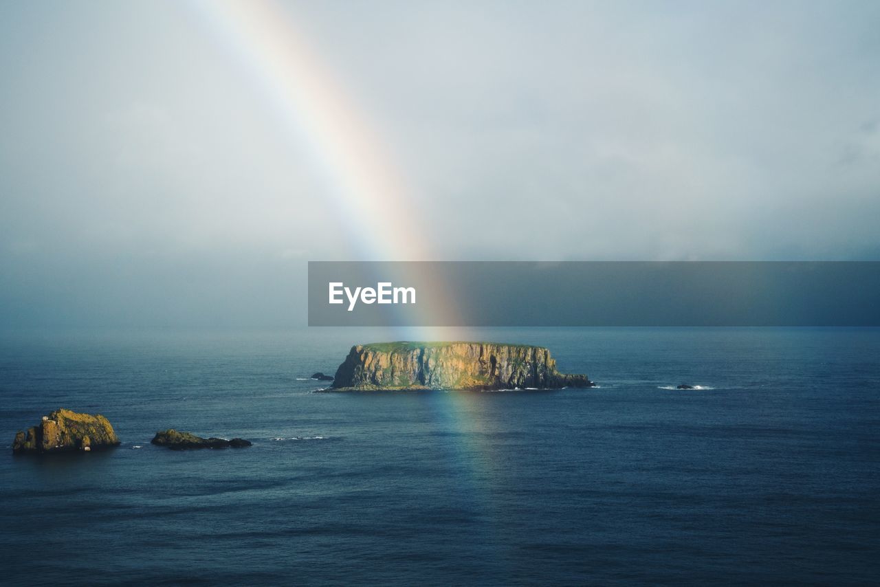 Scenic view of rainbow over sea against sky