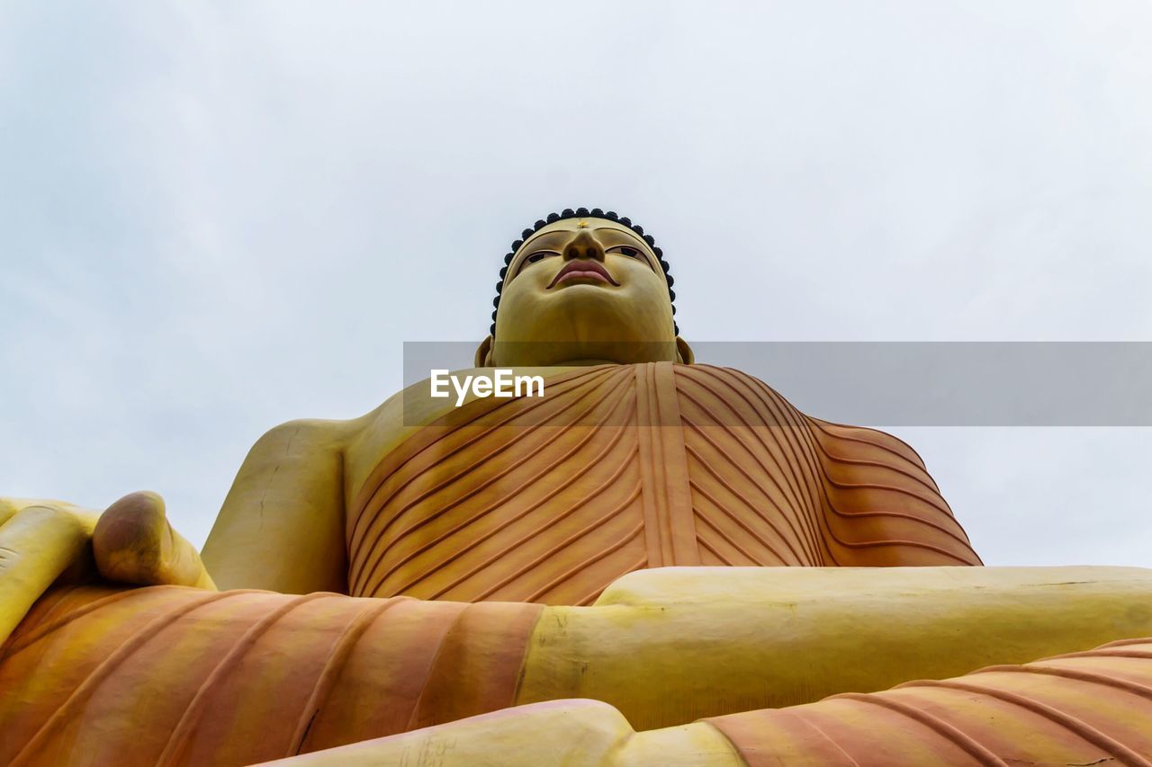 Low angle view of buddha statue against sky