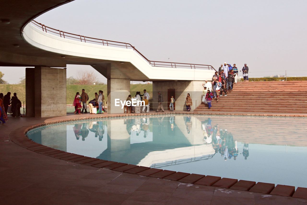 PEOPLE IN SWIMMING POOL AGAINST SKY