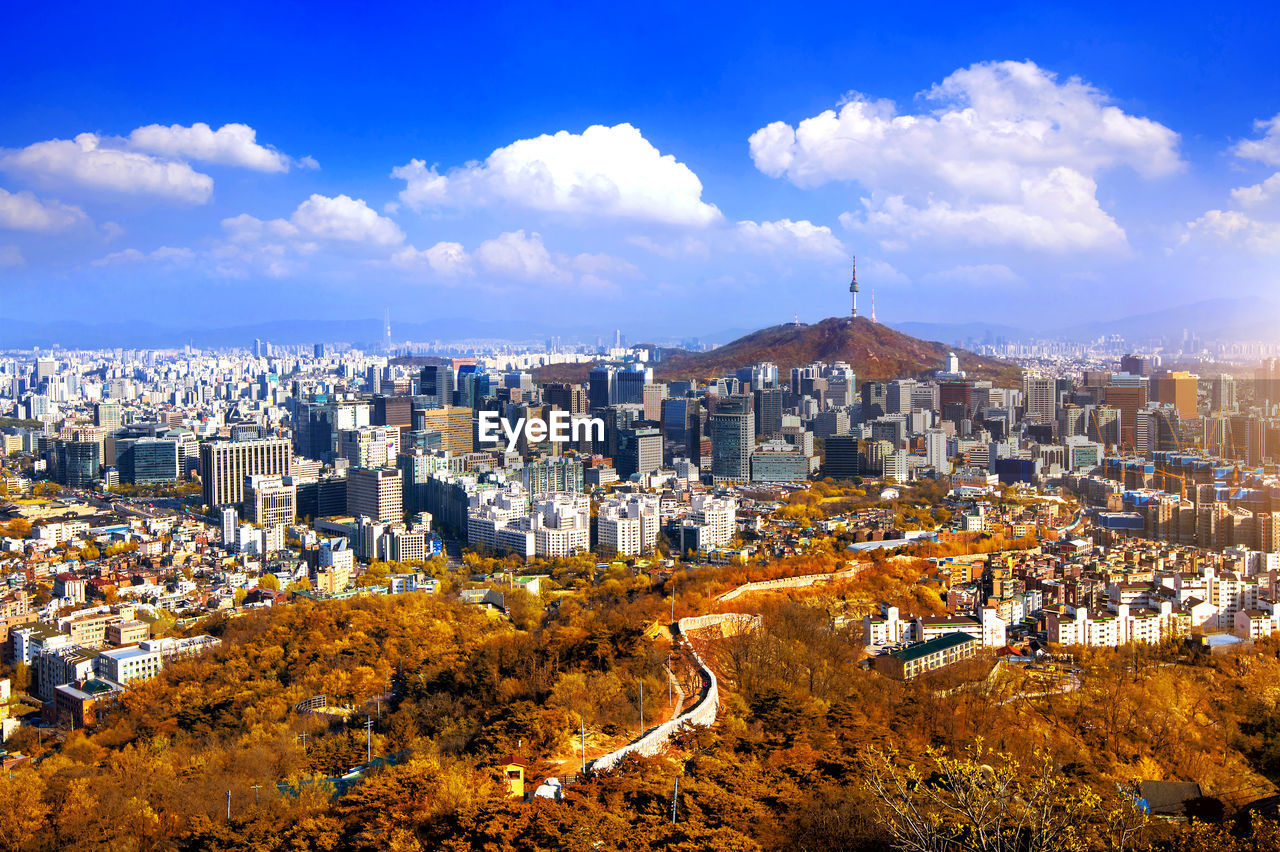 Distant view of n seoul tower on namsan mountain amidst cityscape against sky